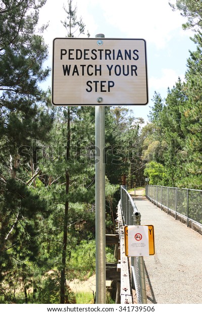Pedestrians\
Watch Your Step sign on a narrow\
footbridge