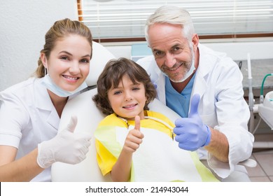 Pediatric dentist assistant and little boy all smiling at camera with thumbs up at the dental clinic - Powered by Shutterstock