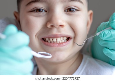 pediatric dentist dental check up happy smiling kid preschooler boy and hand in surgical green gloves with instruments holding mouth mirror explorer probe curve stickle jacquett scaler.diastema gaps 