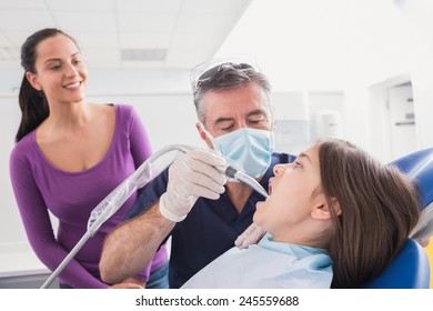 Pediatric Dentist Examining Young Patient With A Suction Tube In Dental Clinic