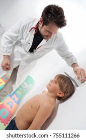 A Pediatric Doctor Controlling The Growth And The Height Of The Child Boy In A Pediatrician Room.