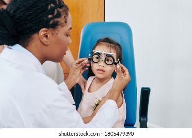 Pediatric Ophthalmologist Checking Vision And Picking Corrective Lenses For Little Girl