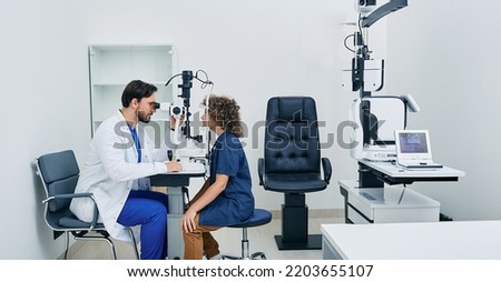 Pediatric ophthalmology. Optometrist checking eyesight of boy patient at modern eye clinic