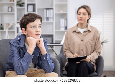 A pediatric psychologist consults a teenage boy, working inside a medical consulting room. - Powered by Shutterstock