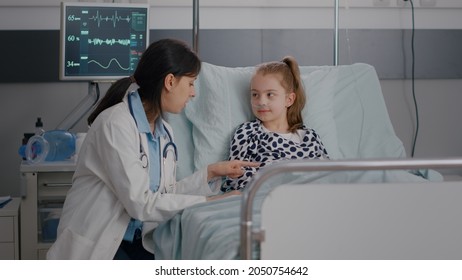 Pediatrician consultant woman doctor interacting with little child giving high five during medicine examination in hospital ward. Sick kid resting in bed after suffering medical surgery - Powered by Shutterstock