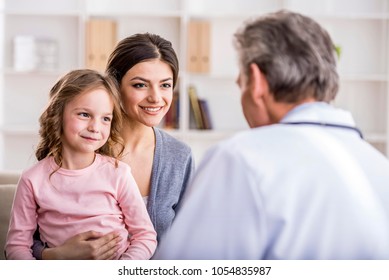 Pediatrician Doctor Examining Child. Mother Holding Baby In Her Hands.