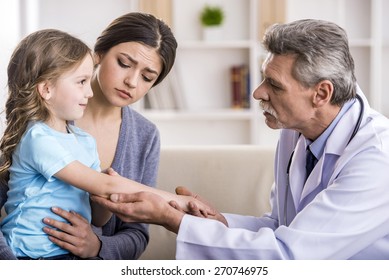 Pediatrician Doctor Examining Child. Mother Holding Baby In Her Hands.