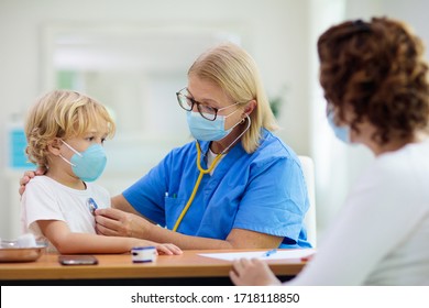 Pediatrician doctor examining sick child in face mask. Ill boy in health clinic for test and screening. Kids home treatment of virus. Coronavirus pandemic. Covid-19 outbreak. Patient coughing.