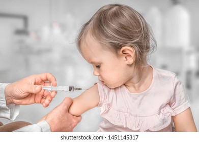 Pediatrician doctor is injecting vaccine to shoulder of baby - vaccination concept