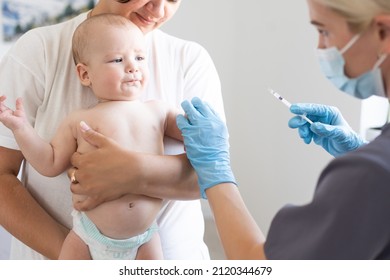 Pediatrician doctor with syringe, tense mother and baby