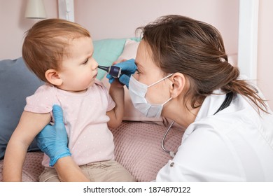 Pediatrician Examines Nose Of Baby Girl At Home During Coronavirus COVID-19 Pandemic Quarantine. Doctor Using Otoscope (auriscope) To Check Nasal Passage Of A Child