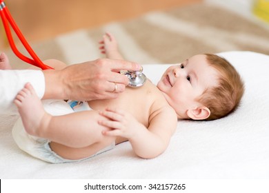 Pediatrician Examines Three Months Baby Boy. Doctor Using A Stethoscope To Listen To Kid's Chest Checking Heartbeat. Smiling Child Looking At Doctor.