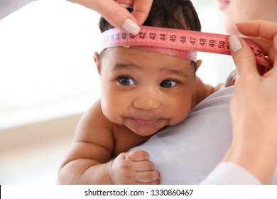 Pediatrician Examining African-American Baby In Clinic