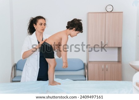 Pediatrician examining child's back posture in clinic.