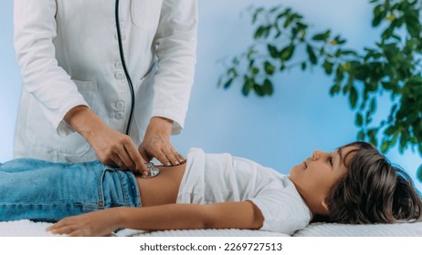 Pediatrician gastroenterologist, medical doctor who specializes in the diagnosis and treatment of gastrointestinal tract disorders doing abdominal examination with stethoscope - Shutterstock ID 2269727513