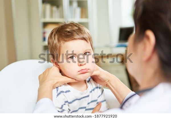 Pediatrician palpates lymph nodes and tonsils in a\
child with a sore\
throat