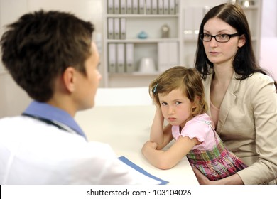 Pediatrician Talking To Mother And Upset Child At Office