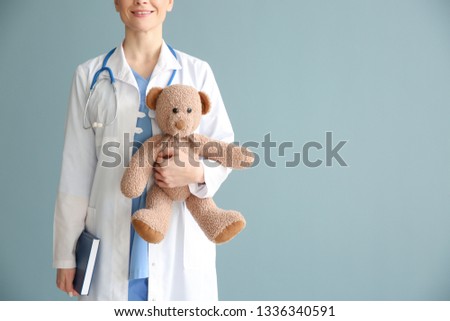 Pediatrician with toy on color background