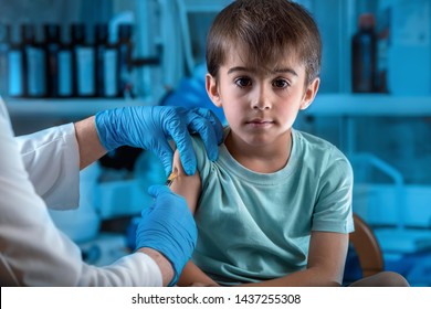 pediatrician vaccinating child in the pediatric clinic / doctor injecting vaccine preventive to little boy in the hospital