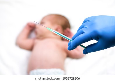 Pediatrician vaccinating newborn baby. Vaccine, Vaccination for infant child Soft focus Syringe in hands of a nurse and blurred background of infant  baby on white. Doctor in blue gloves close up.