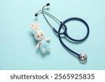 Pediatrics concept. Toy bunny with stethoscope on light blue background, top view