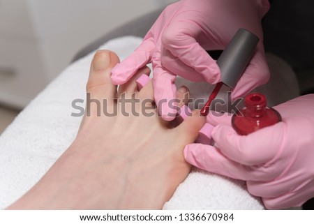 Pedicure in beauty salon. Nail polishing with red nail polish. Close up