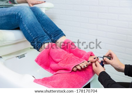 Pedicure chair spa and woman hands painting toes nail polish after bath with pink towel
