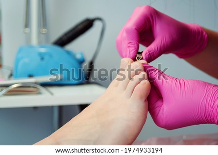 Pedicure master cuts toenails during pedicure procedure. Professional pedicure in the beauty salon. The beautician cuts the skin with fingernails and performs professional pedicure.