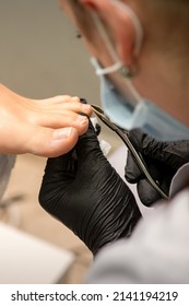 Pedicure Master Using Nail Nippers While Trimming Toenails In A Pedicure Salon.