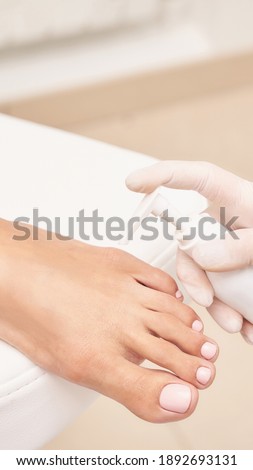 Pedicure nail spa procedure. Foot manicure. Salon master. Polish woman leg. Hands in gloves. Light background. Massage service. Healthy toe cleaning. Pink pastel color. Dermatology cream