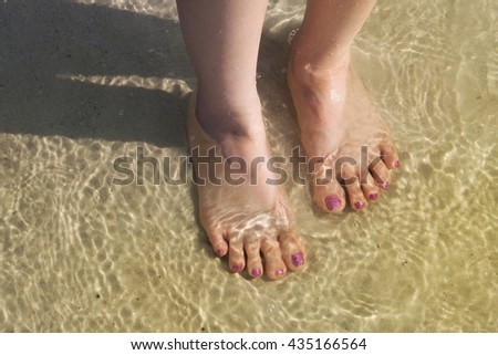 Pedicure on foot in the water on the sand