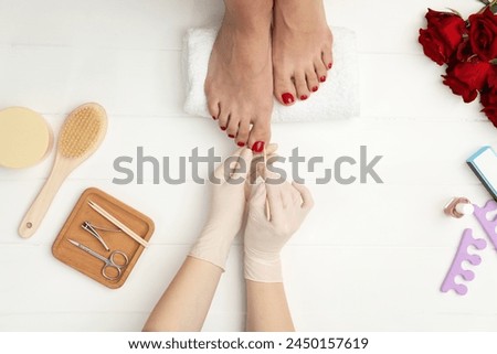 Pedicurist working with client`s toenails in beauty salon, top view