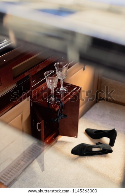 Peek inside a retro luxury car with\
a couple of champagne glasses, untied bow tie and fancy women\'s\
shoes on a carpet. Romantic, slightly erotic\
mood
