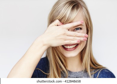 Peeking young blond woman smiling at camera