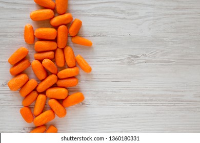 Peeled Baby Carrots Ready To Eat On A White Wooden Background, Top View. Overhead, From Above, Flat Lay. Copy Space.