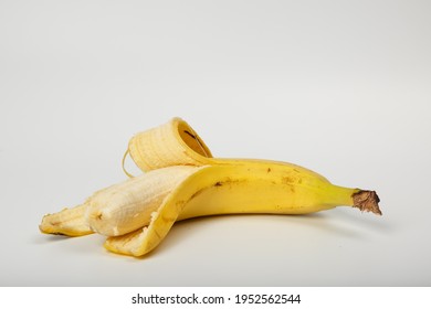 A peeled and bitten banana in a peel on a white background. Old one peeled banana. Tropical yellow fruit. Selective focus. Bitten Banana.