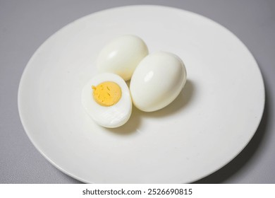 peeled boiled eggs placed on a plain white plate. The surface of the eggs is smooth. The setting appears simple and minimalistic. - Powered by Shutterstock