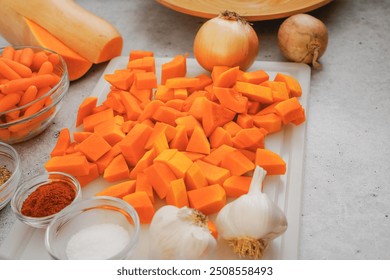 Peeled and chopped butternut squash, carrot, garlic, and onion close-up. Butternut squash soup recipe, ingredients on a kitchen table - Powered by Shutterstock