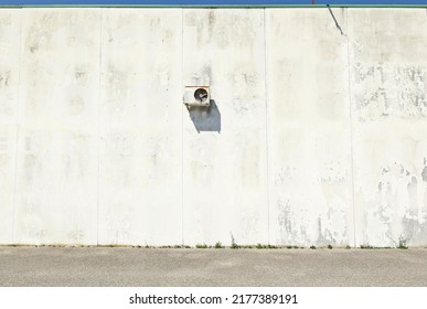 Peeled concrete block wall with  rusty exteror box of air conditioner  hanging. Asphalt street in front. Grunge background for copy space 