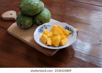 Peeled mango slices on a white plate on wooden cutting board in wooden table background, a whole ripe mango placed beside, Fresh fruit. Tropical fruit - Powered by Shutterstock