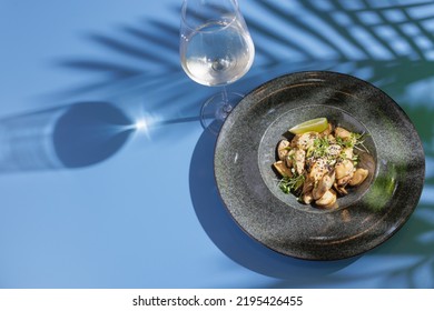 Peeled Mussels On A Dark Plate With Lemon On A Blue Background With A Shadow From A Palm Tree, Top View