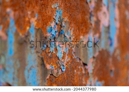 Peeled off paint on rusty vehicle surface of a ruined train. Vintage metal background with wheathered rotten color and massive corrosion in shades of blue, brown and turqouise with selective focus.