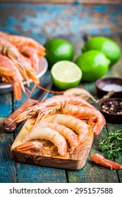 Peeled Raw Prawns On A Wooden Cutting Board With Salt, Pepper, Lime On A Rustic Table