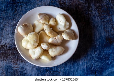 Peeled Water Chestnut Or Eleocharis Dulcis Aquatic Fruit In A Plate Isolated On Bluish Background