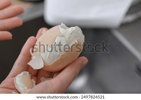 Peeling a boiled egg from its shell, the shell does not come off easily, close-up