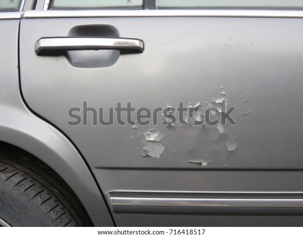 Peeling\
of car color on the door of the silver color\
car
