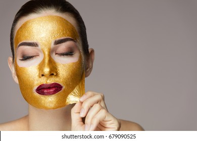 Peeling Cosmetic Gold Mask From Beautiful Face Skin. 