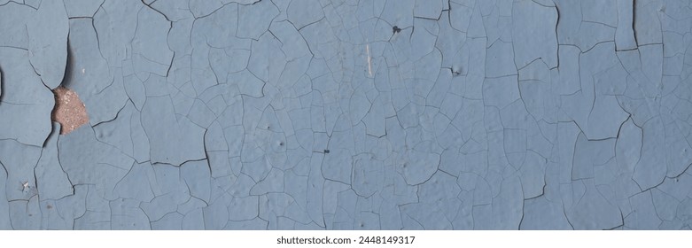 Peeling paint on the wall. Panorama of a concrete wall with old cracked flaking paint. Weathered rough painted surface with patterns of cracks and peeling. Panoramic texture for background and design.