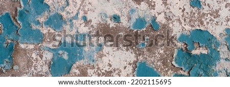 Peeling paint on the wall. Panorama of a concrete wall with old cracked flaking paint. Weathered rough painted surface with patterns of cracks and peeling. Wide panoramic texture for design background