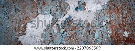 Peeling paint on the wall. Panorama of a concrete wall with old cracked flaking paint. Weathered rough painted surface with patterns of cracks and peeling. Wide panoramic texture for design background